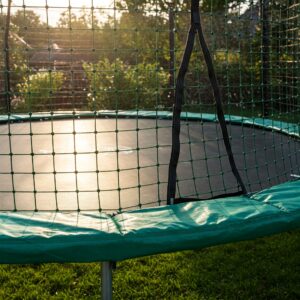 Detailed view of the durable safety netting enclosing an oval trampoline, highlighting its protective features.