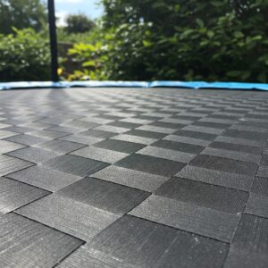 Close-up of the durable, woven mat on a trampoline without springs, highlighting its safety features.