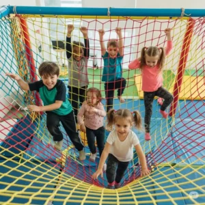 Children enthusiastically climbing a colorful net in an indoor kids gym, promoting physical activity and adventure.