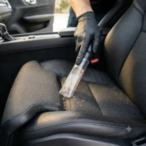 Using a vacuum crevice tool attachment to clear debris before learning how to clean car seat safely without damage.
